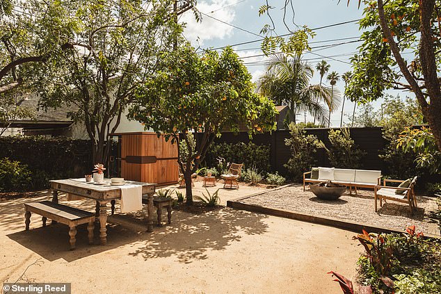 The backyard features plenty of seating areas and a sauna alongside lush greenery.