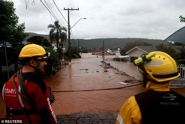 Rescue workers stand near a flooded area next to the Taquari River during heavy rains in Encantado in Rio Grande do Sul on May 2, 2024
