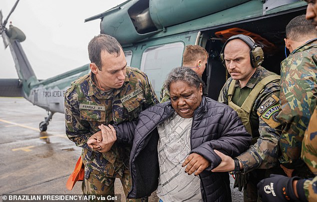 This handout picture released by the Brazilian Presidency shows a woman being assisted by members of the Air Force after being rescued in a helicopter from a flooded area of Rio Grande do Sul State, at the Santa Maria Air Base in southern Brazil, on May 2