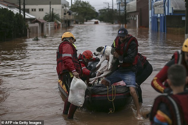 Firefighters rescue a man and his dog from a flooded area at the city center of Sao Sebastiao do Cai, Rio Grande do Sul on May 2