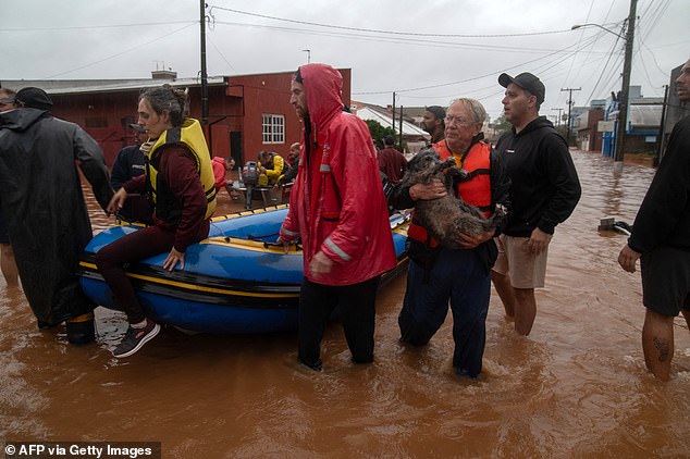 Residents and a dog are evacuated from a flooded area in the city center of Sao Sebastiao do Cai, Rio Grande do Sul State on May 2