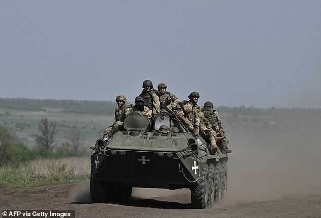 Ukrainian servicemen ride an armored personnel carrier (APC) in a field near Chasiv Yar, Donetsk region, April 27, 2024.