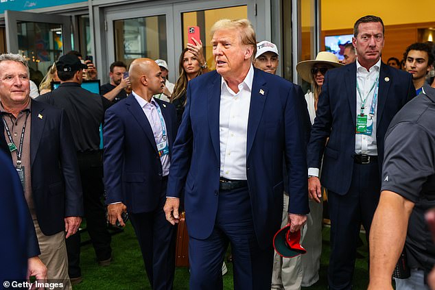 Former US President Donald Trump is escorted through the paddock before the race