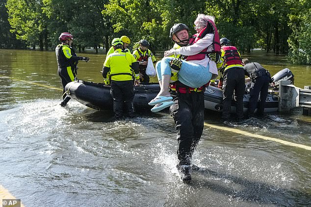 A Conroe firefighter is seen carrying an elderly woman to safety after her home flooded in Conroe, Texas.