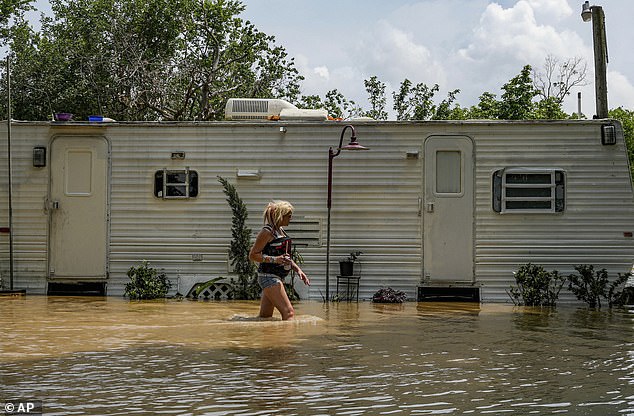 A woman is seen wading through brown flood water as she heads to check on an elderly resident inside her mobile home in Channelview, Texas.