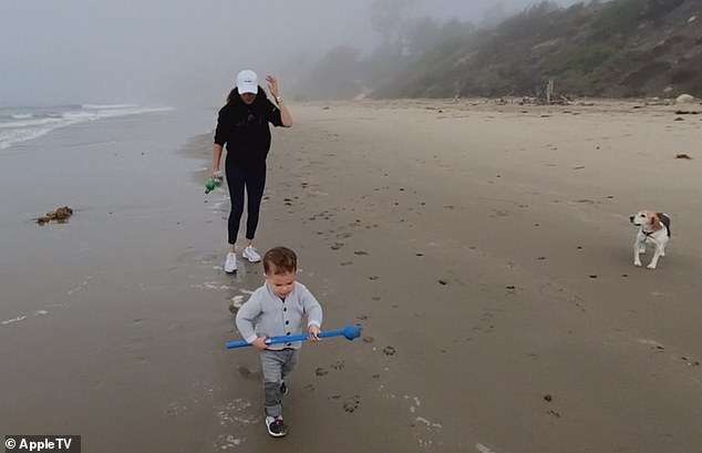 Archie walks on the beach with his mother and their pet beagle, Guy.