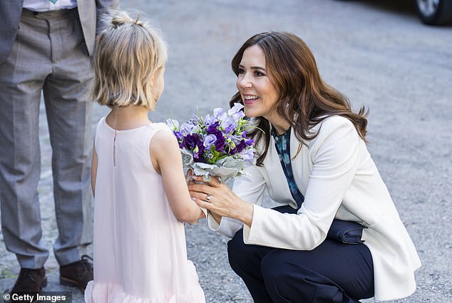 The queen knelt down to reach the girl, gently took the bouquet and shared a sweet chat with the girl.