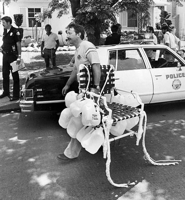 Larry passes a police car while carrying his lawn chair after a crash landing from his balloon getaway in the sky.