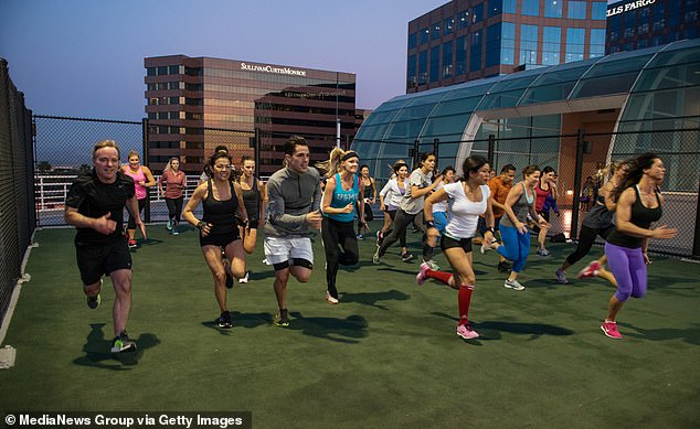 Men and women sprint around the Equinox rooftop training area as part of a Tabata class in Irvine, California.