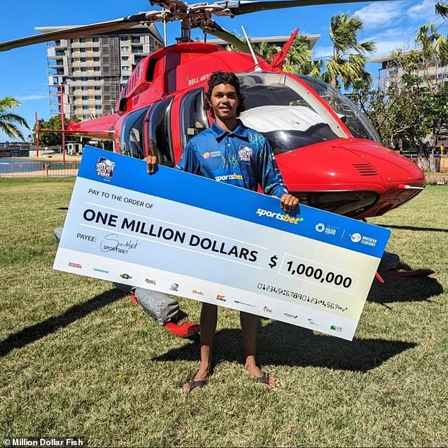 Keegan Payne with his huge $1 million prize after catching a tagged barramundi in the long-running competition, which was his first win in nine fishing seasons.