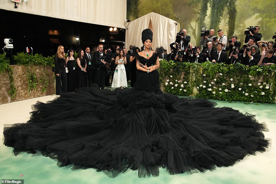 Cardi stunned on the red carpet in a black tulle dress that required up to nine men to unfold the fabric around her.