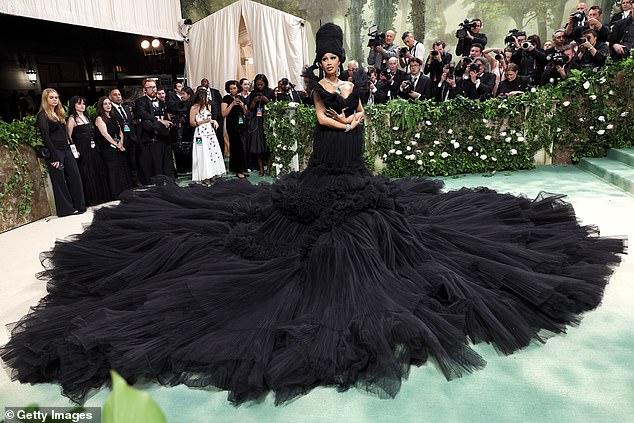 Cardi B needed no less than five assistants to arrange her black lace dress around her and prepare her for this red carpet pose.