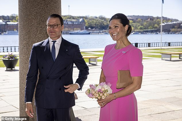 The Swedish royal, 46, looked summed up in a bright pink dress as she arrived at City Hall with her husband Prince Daniel (left) on Tuesday, ahead of a meal with Queen Mary of Denmark and King Frederick X.