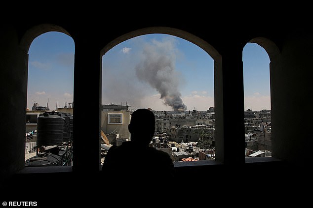 A Palestinian man watches smoke rise after Israeli attacks as Israeli forces launch a ground and air operation in the eastern part of Rafah.