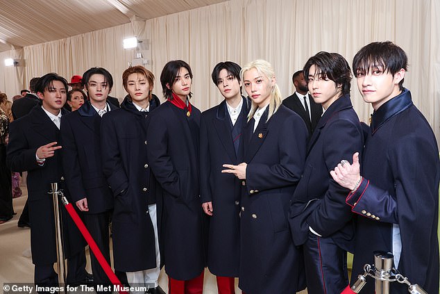 The band were all smiles as they arrived before a carefully orchestrated red carpet routine saw them pose several meters away from each other before removing their coats to reveal their outfits.