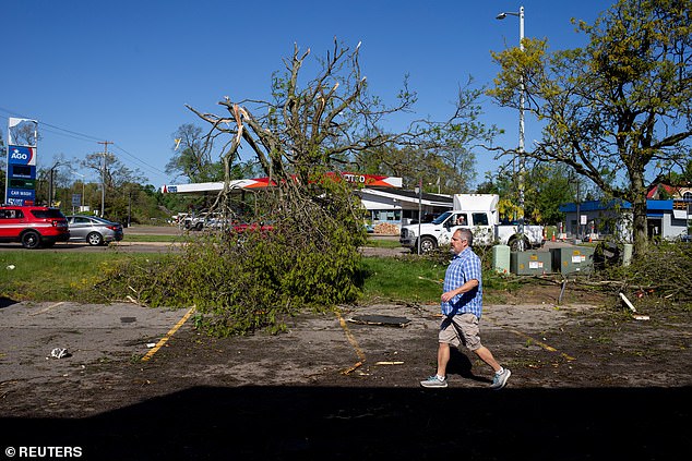 A resident walks past uprooted trees near damaged businesses and buildings after a tornado hit the Portage area.