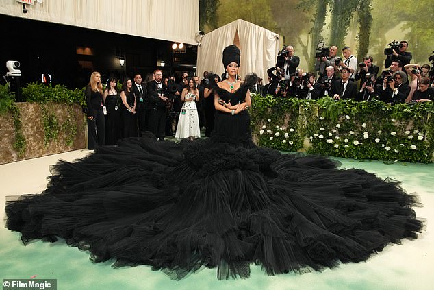 Cardi stunned on the red carpet in a black tulle dress that required up to nine people to unfold the fabric around her.