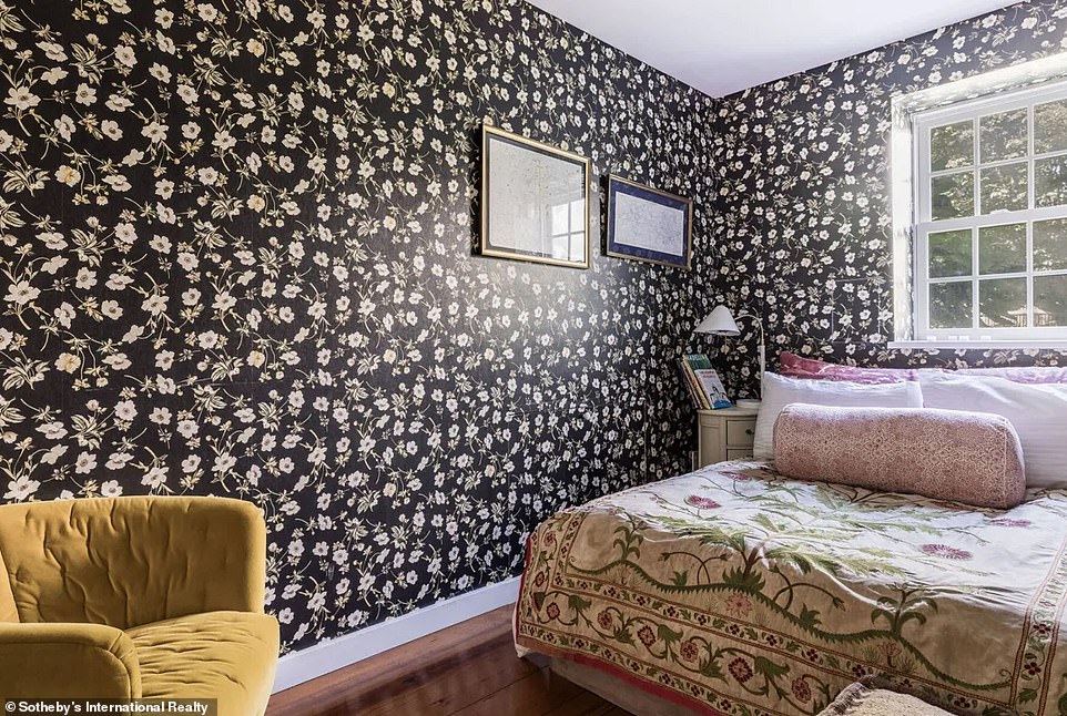 Another bedroom features eye-catching wallpaper with a floral print on a black field, which pairs elegantly with the brown hardwood floors.