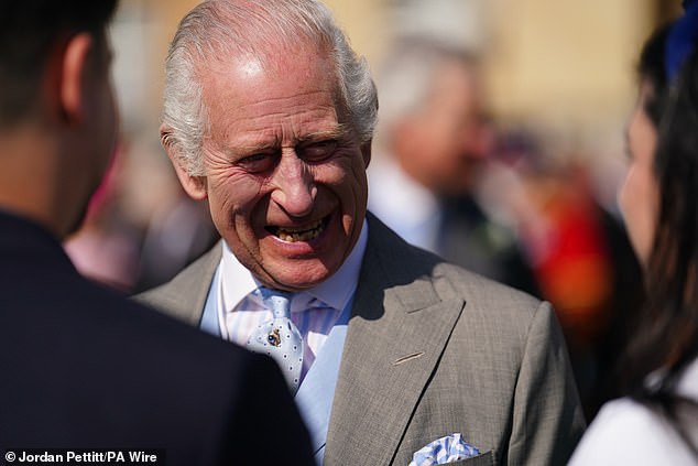 King Charles III speaks to guests attending the Buckingham Palace garden party today