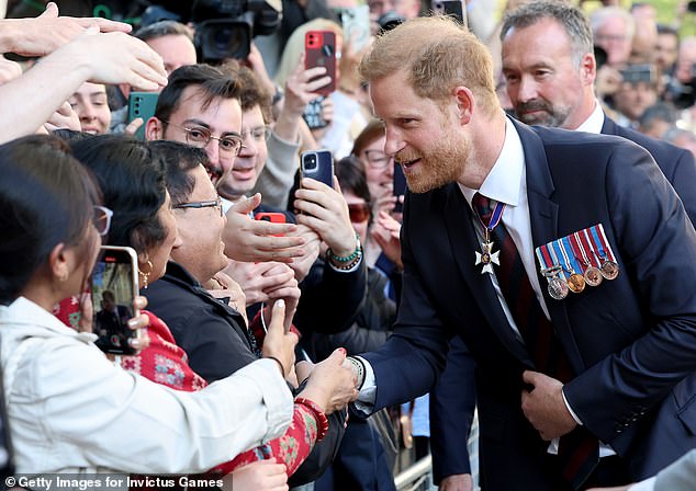 Prince Harry shakes hands with fans waiting to greet him outside St Paul's yesterday