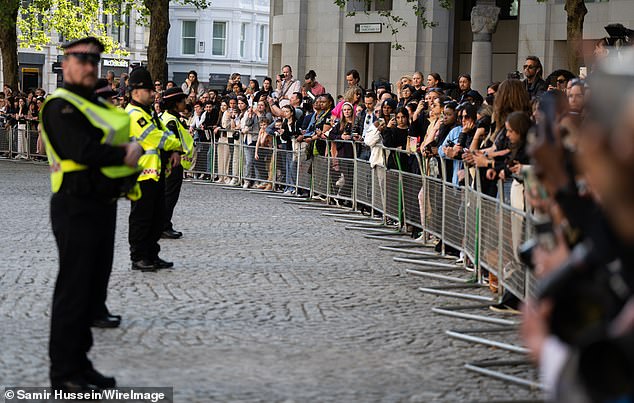 Police officers monitor the crowd waiting to meet Harry outside St Paul's Cathedral yesterday.