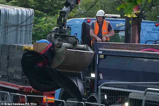 A crane operator removes the tents from the waterfront and loads them onto a truck to take them away.