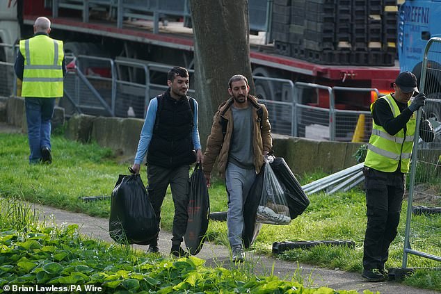 Asylum seekers leave with their belongings during a morning operation by Irish authorities to remove tents.