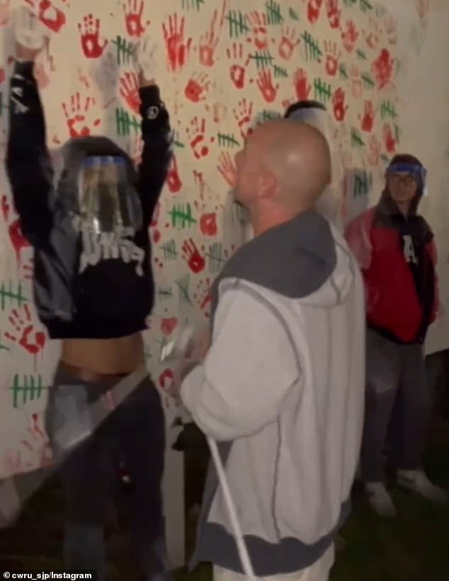 The contractor nonchalantly sprays protesters leaning against graffiti as he attempts to cover up the mess, but is confronted by activists who refuse to leave.