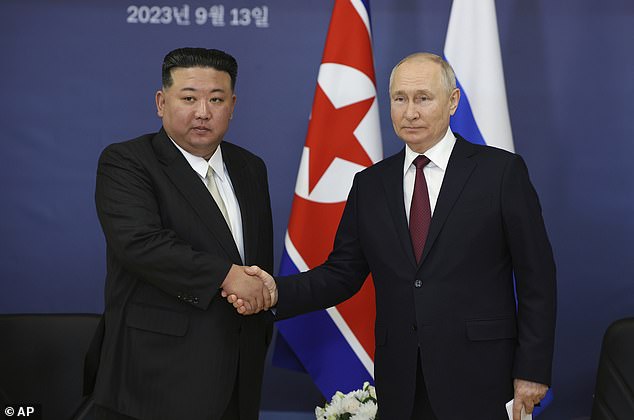 Russian President Vladimir Putin (right) and North Korean leader Kim Jong Un shake hands.