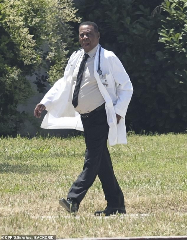 Courtney B. Vance wore a doctor's uniform as she walked to the set.