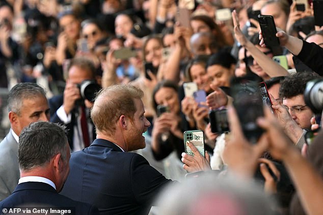 Fans take pictures as Prince Harry shakes hands outside St Paul's Cathedral yesterday