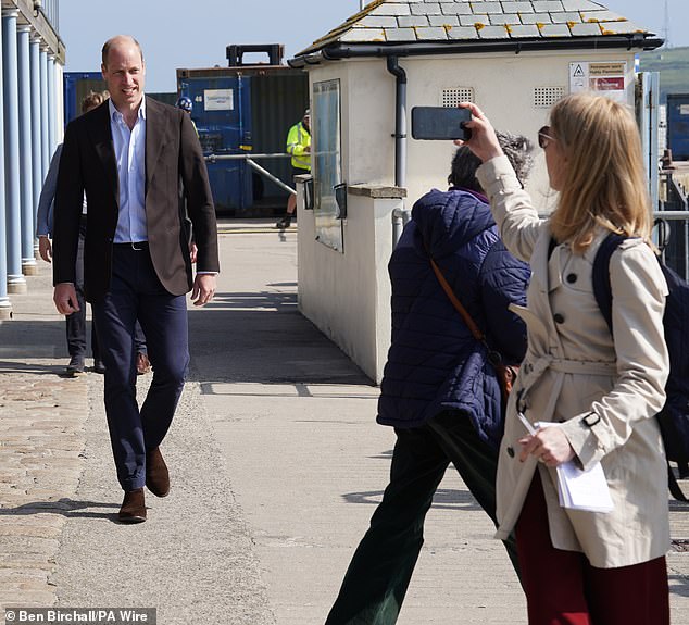 Smile! A spectator takes a photograph of the royal as he makes his way to the St Mary's pier area.