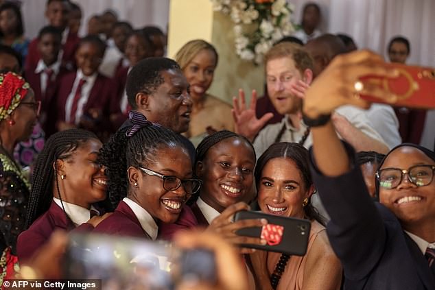 Meghan takes a selfie with students as Harry looks on at Wuse Lightway Academy today