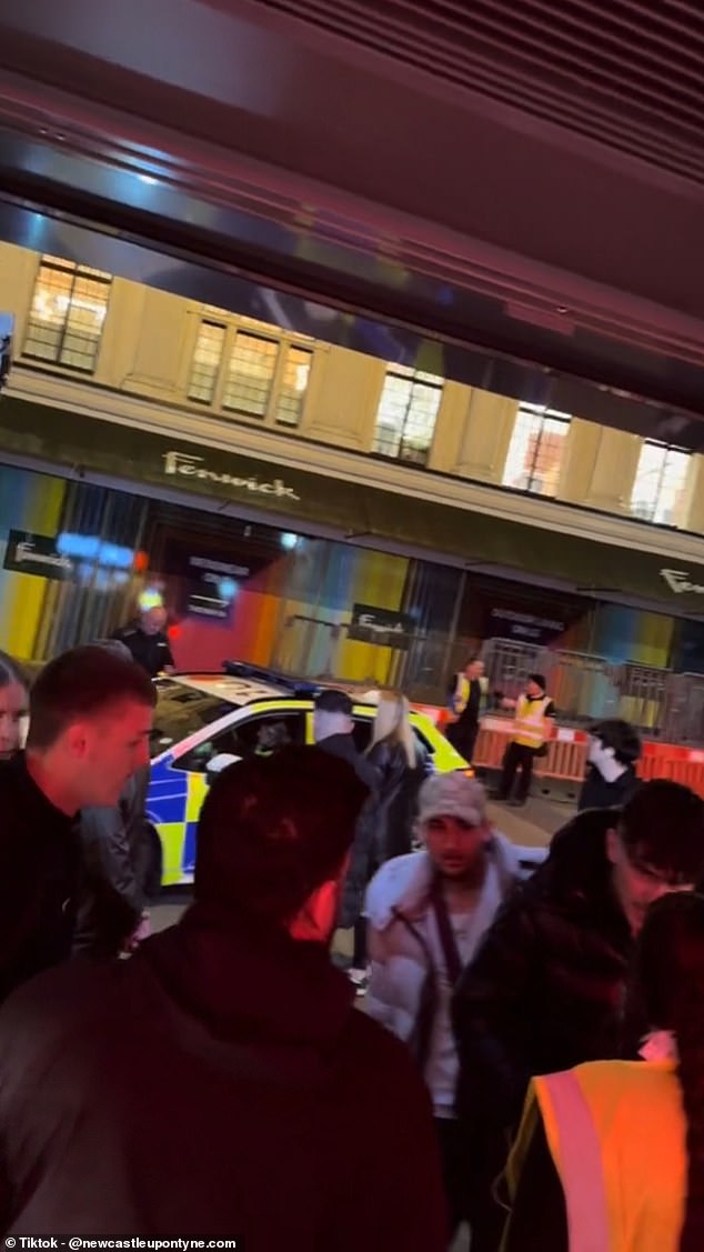 A marked police car sits idle outside the venue, with a Fenwick department store in sight across the street, as the rave takes place.