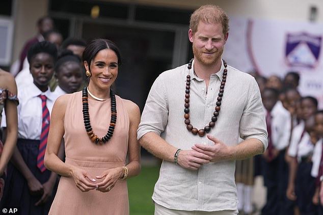 Harry and Meghan are pictured smiling as they begin their tour of Nigeria with a trip to Wuse Lightway Academy today.