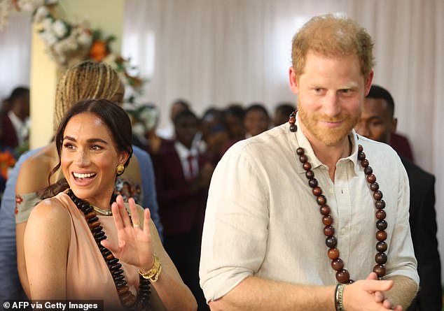 Prince Harry and Meghan Markle smiled as they arrived at the Wuse Lightway Academy in Abuja this morning.