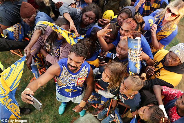 Liam Ryan of the Eagles takes some selfies with a large crowd of fans in Alice Springs