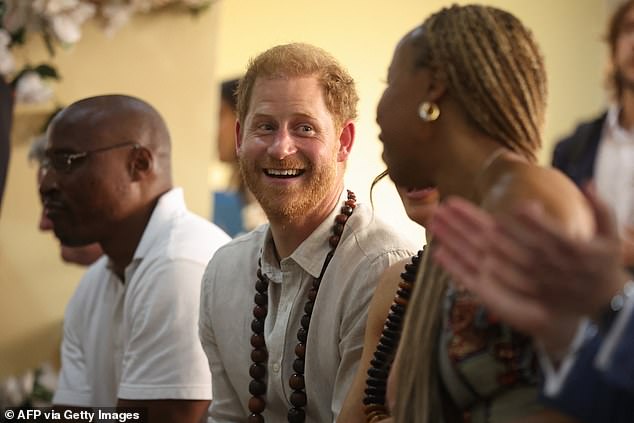 Prince Harry speaks to those sitting with him at the Wuse Lightway Academy in Abuja on Friday.