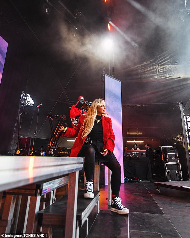 Her long blonde hair fell over her shoulders in dramatic curls, while a gold chain necklace added a touch of glamor to her rock n' roll ensemble.