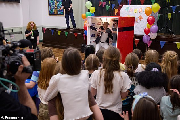 The music mogul and former Strictly Come Dancing judge is then seen emerging from the box to be greeted by a crowd of screaming and cheering children.