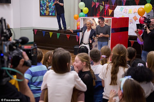 One of the children bravely asks: Are you the real Simon Cowell? To which the head judge responds by lifting his sunglasses and exclaiming: Yes!