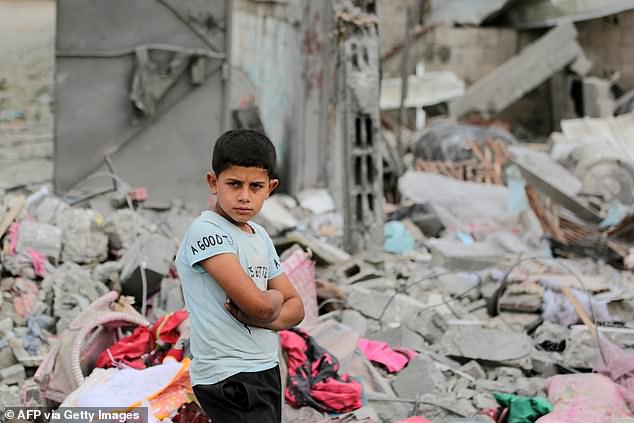 A Palestinian boy lies in the rubble of a residential building destroyed by an Israeli strike in Al-Zawayda, central Gaza Strip.