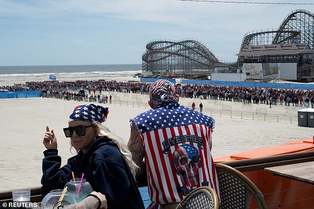 A man and woman hang out on the Wildwood boardwalk, where below thousands of Trump supporters wait in line for Saturday's Jersey Shore rally.