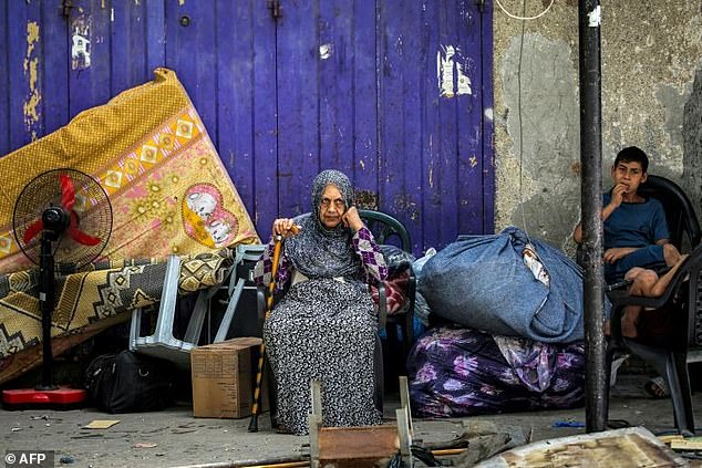 An elderly woman and a child wait with their belongings before evacuating from Rafah, following an order from the Israeli army.