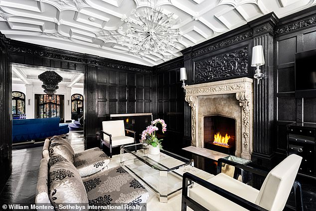 A cozy fireplace adds some warmth to this black and white carved wood room.