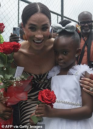 The Duchess posed happily with onlookers, including a young woman, elegantly dressed in a white dress and matching bow.