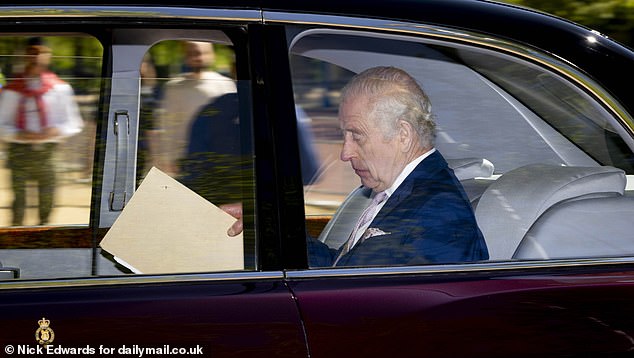 King Charles III is pictured holding papers as he arrives at Clarence House in London on Tuesday, as Harry was set to arrive.