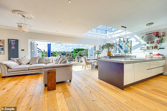 The main living room has oak floors and bi-fold doors that extend along one wall and open onto the garden.