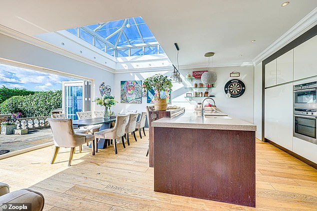 The open plan large living room houses a modern kitchen with island and dining area.