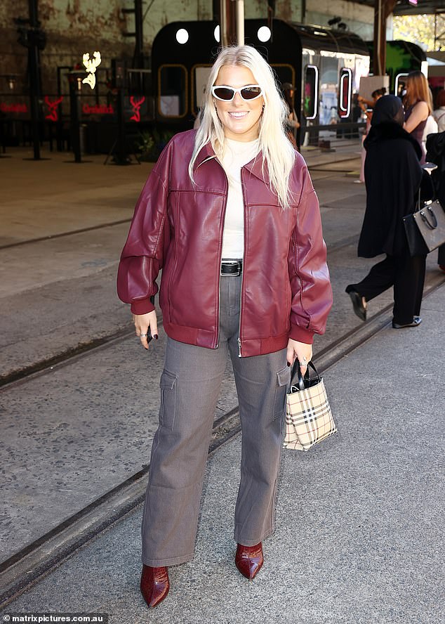 Shane Warne's daughter Brooke put on a fashionable display in a red leather jacket and gray cargo pants as she smiled for the cameras.